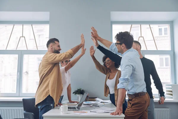 Gruppo di giovani uomini d'affari fiduciosi in abbigliamento casual intelligente che si tengono per mano e sorridono — Foto Stock