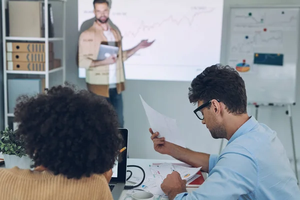 Groep van jonge moderne mensen in slimme casual wear analyseren van gegevens op projectiescherm in het kantoor — Stockfoto