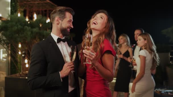 Красивая молодая пара пьет шампанское, проводя время на роскошной вечеринке — стоковое видео