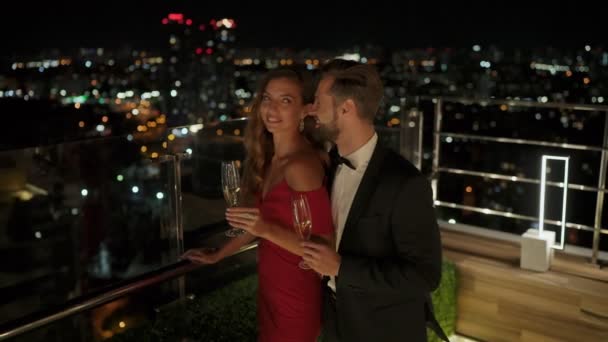 Красивые молодые люди держат флейты с шампанским и веселятся на вечеринке на крыше — стоковое видео