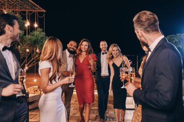 Bir grup güzel insan resmi kıyafetler içinde iletişim kuruyor ve gülümsüyor ve lüks bir partide vakit geçiriyorlar.