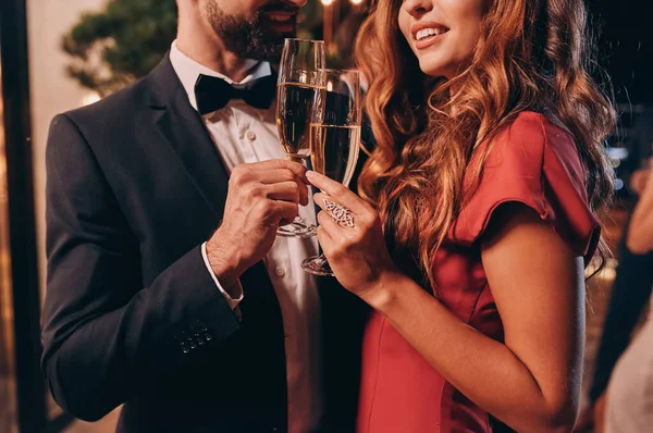 Primer plano de hermosa pareja joven en tostadas de ropa formal con champán mientras pasa tiempo en una fiesta de lujo —  Fotos de Stock