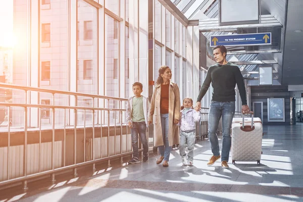 Повна довжина щасливої сім'ї з двома маленькими дітьми, що ходять по терміналу аеропорту — стокове фото