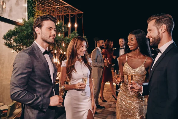 Grupo de personas en ropa formal comunicándose y sonriendo mientras pasan tiempo en una fiesta de lujo — Foto de Stock