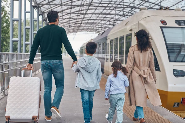Vue arrière de la famille avec deux petits enfants marchant ensemble sur le quai de la gare — Photo