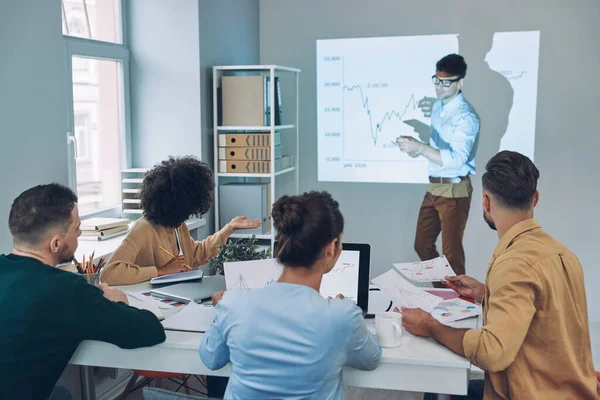 Grupo de jovens modernos em desgaste casual inteligente analisando dados na tela de projeção no escritório — Fotografia de Stock