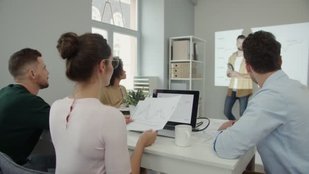 Grupo de jóvenes en ropa casual inteligente analizando datos en la pantalla de proyección — Vídeo de stock