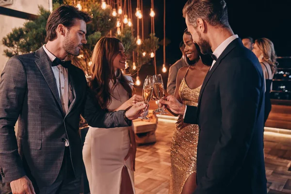 Gruppo di persone in formalwear brindare con champagne e sorridere mentre trascorrono del tempo alla festa di lusso — Foto Stock