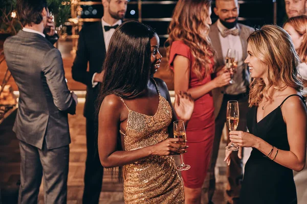 En grupp vackra unga människor i formalwear kommunicerar och ler samtidigt som de tillbringar tid på lyxig fest — Stockfoto