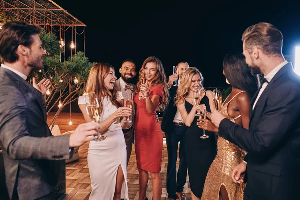 Grupo de gente hermosa en ropa formal comunicándose y sonriendo mientras pasa tiempo en una fiesta de lujo — Foto de Stock