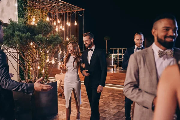 Grupo de personas en ropa formal comunicándose y sonriendo mientras pasan tiempo en una fiesta de lujo — Foto de Stock