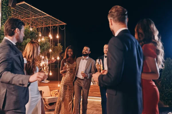 Gruppe von schönen Menschen in Formalbekleidung kommunizieren und lächeln, während sie Zeit auf einer Luxusparty verbringen — Stockfoto