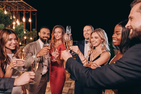 Grupo de pessoas bonitas em formalwear brindar com champanhe e sorrindo enquanto passa o tempo em festa de luxo — Fotografia de Stock