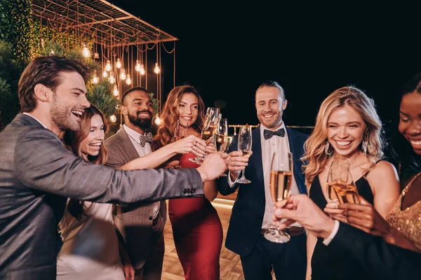 Grupo de gente hermosa en ropa formal comunicándose y sonriendo mientras pasa tiempo en una fiesta de lujo — Foto de Stock