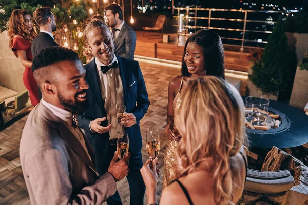 Gruppo di persone in abbigliamento formale che comunicano e sorridono mentre trascorrono del tempo alla festa di lusso — Foto Stock