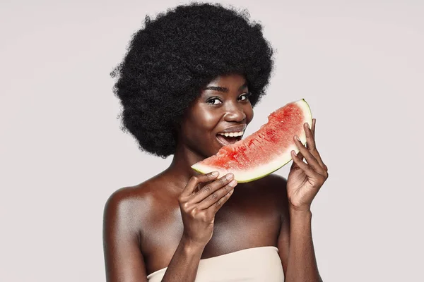 Portret van een mooie jonge Afrikaanse vrouw met een plak watermeloen en een glimlach — Stockfoto