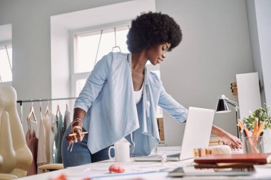 Moda tasarım stüdyosunda masasında çalışan güzel bir Afrikalı kadın.