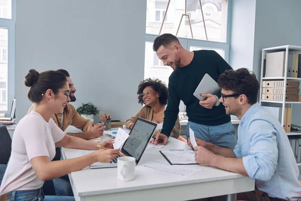 Gruppe selbstbewusster junger Leute in schicker Freizeitkleidung diskutiert Geschäfte, während sie sich im Büro treffen — Stockfoto