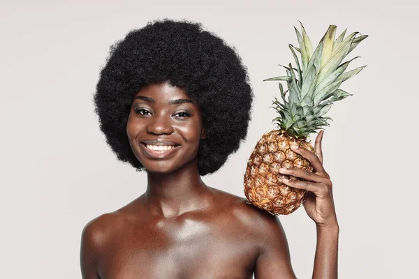 Portrait de belle jeune femme africaine tenant l'ananas sur l'épaule et souriant — Photo