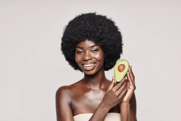 Portré gyönyörű fiatal afrikai nő gazdaság avokádó és mosolygós — Stock Fotó