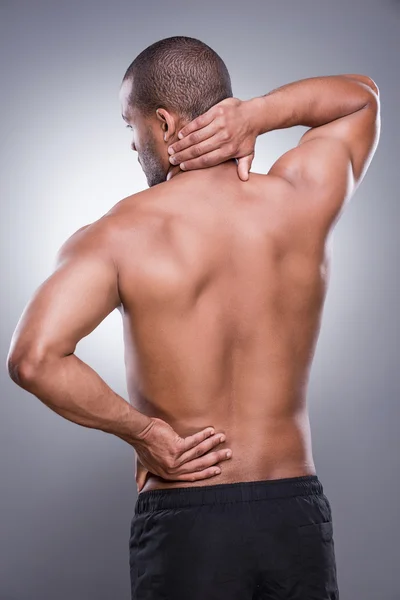 Uomo africano muscolare che si tocca l'anca e il collo — Foto Stock