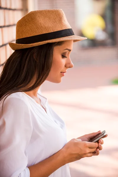 Vrouw in funky hoed te typen op mobiele telefoon — Stockfoto