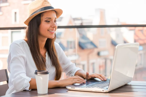 Frau mit flippigem Hut arbeitet am Laptop — Stockfoto