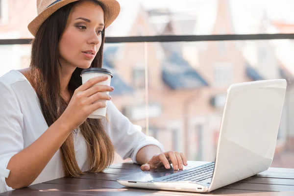 Woman working on laptop and drinking coffee — Stock Photo, Image