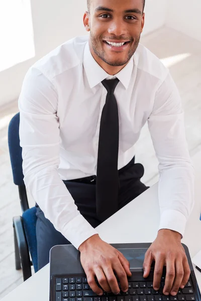 Hombre africano en camisa y trabajando en el ordenador portátil — Foto de Stock