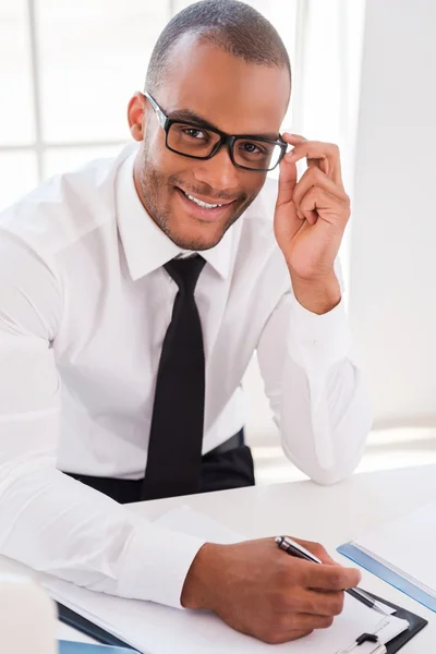 African man in shirt and tie writing at clipboard — Stock Photo, Image