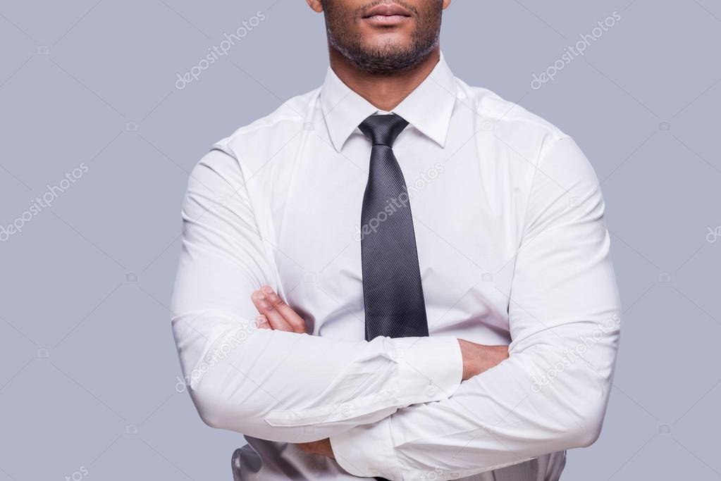 African man in shirt and tie keeping arms crossed