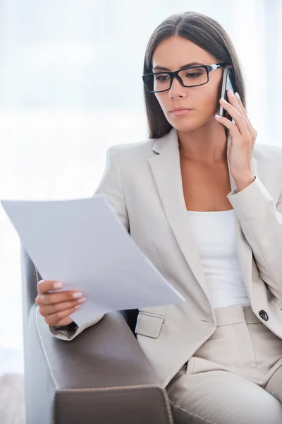 Бізнес-леді вивчає документ і розмовляє по телефону — стокове фото