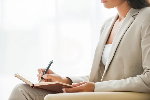 Empresaria en traje escribiendo en bloc de notas — Foto de Stock