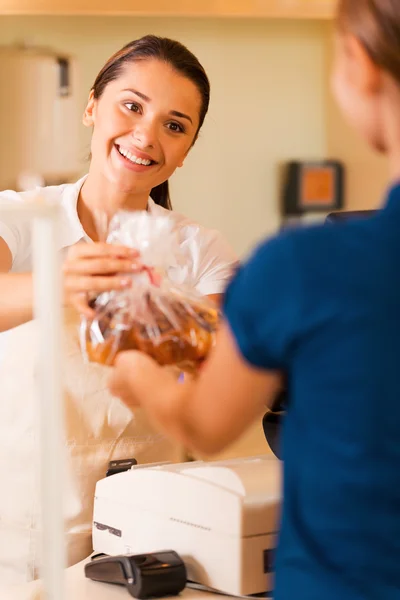 Fêmea padeiro dando biscoitos ao cliente — Fotografia de Stock