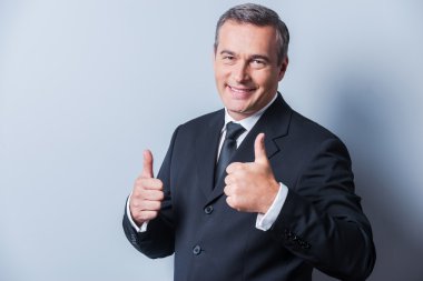 başparmaklarını gösterilen resmi kıyafeti içinde olgun adam