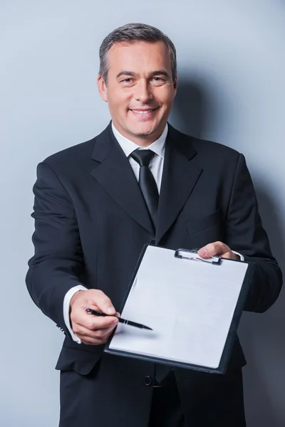 Mature man in formalwear stretching out clipboard — Stock Photo, Image