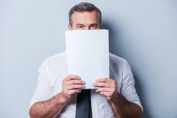 Mature man in formalwear hiding face behind documents — Stock Photo, Image