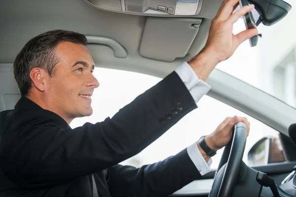 Mogen man i formalwear justera spegeln i bil — Stockfoto