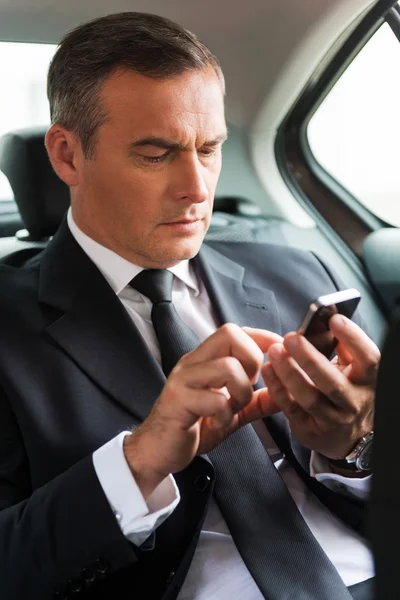 Uomo d'affari digitando messaggio in auto — Foto Stock