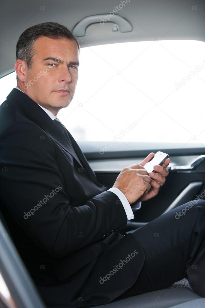 Businessman typing message in car