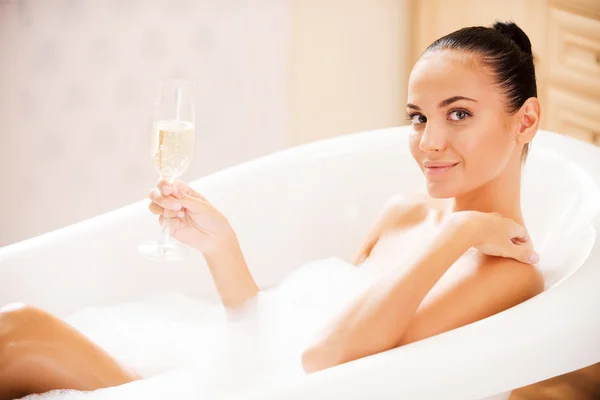 Woman holding wine glass in bubble bath — Stock Photo, Image