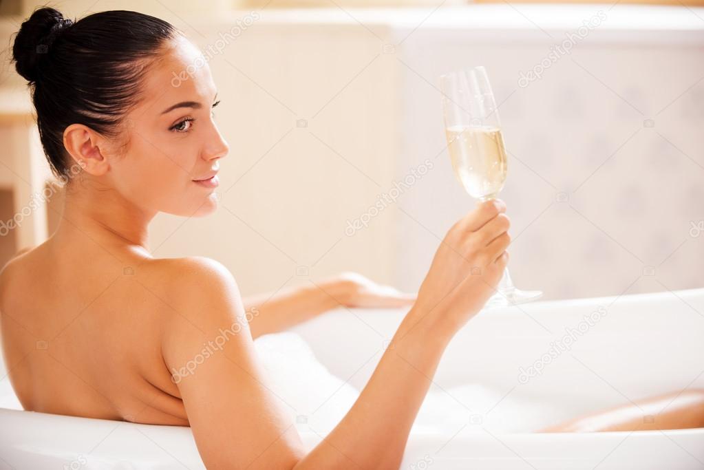 Woman holding glass with wine in bath