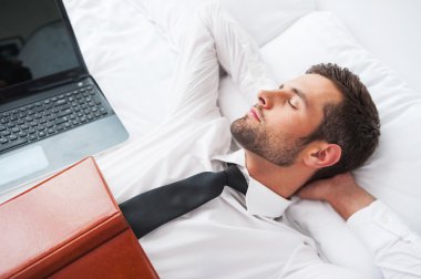 otel odasında yatakta yatan kravatlı adam