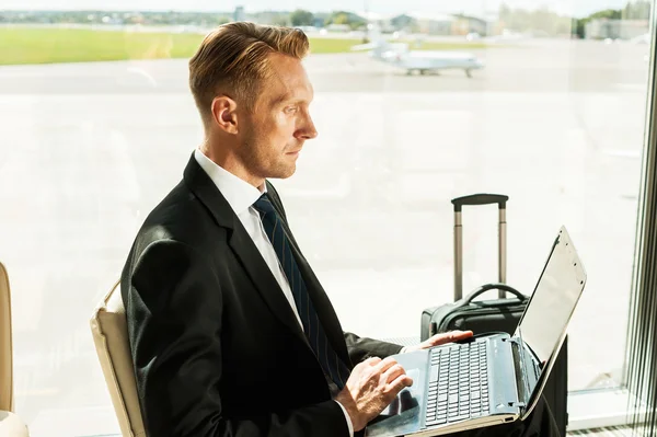 Бизнесмен, работающий над ноутбуком в аэропорту — стоковое фото