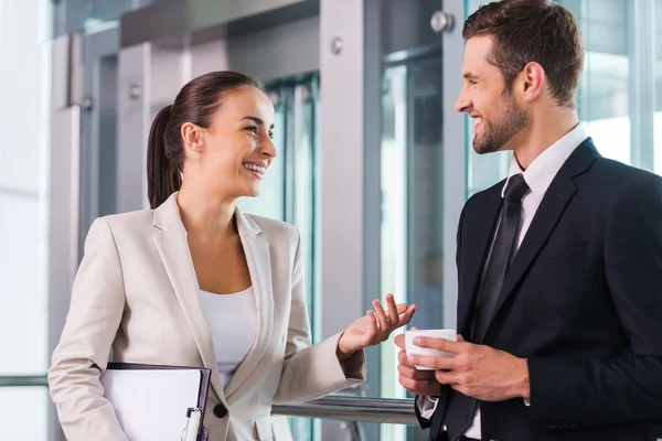 Taking time to chat with colleague. Two cheerful business people discussing something and smiling — Stock Photo, Image