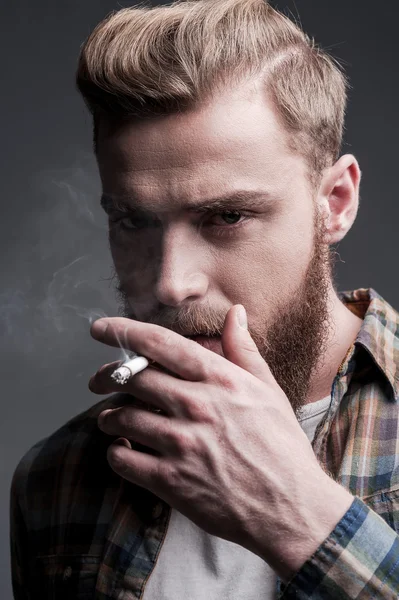 Молодой бородатый мужчина курил сигарету — стоковое фото