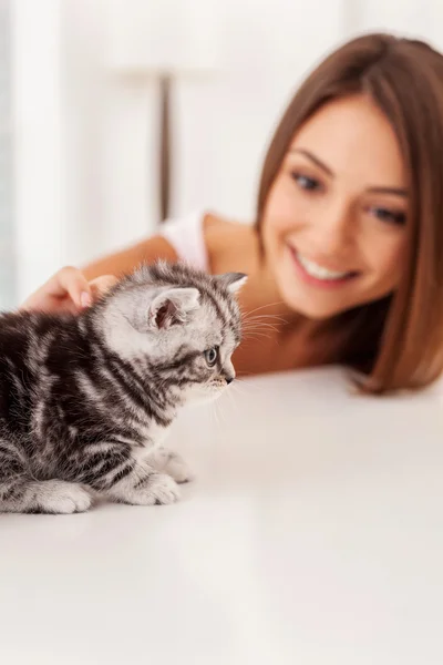 Kätzchen sitzt mit junger Frau auf dem Tisch — Stockfoto