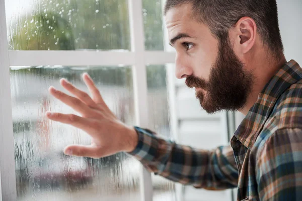 Bärtiger Mann, der das Fenster berührt — Stockfoto