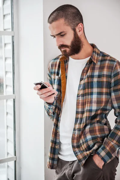 Бородатый человек печатает сообщение на смартфоне — стоковое фото