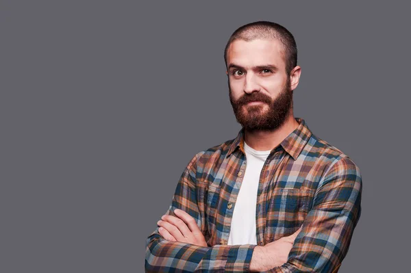 Hombre barbudo manteniendo los brazos cruzados y expresando una sonrisa irónica — Foto de Stock